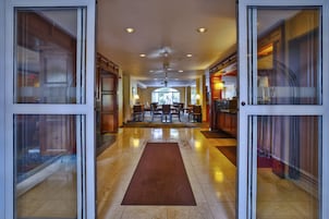 Un hall de hotel con una zona de estar central, un mostrador de recepción y vistas al exterior a través de amplios ventanales.