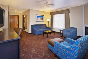 A hotel room with a sofa, armchair, coffee table, and a TV. - Holiday Inn Express Mackinaw City by IHG (Mackinaw City)