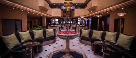 A lobby with a central fountain, sofas, and a bar area.