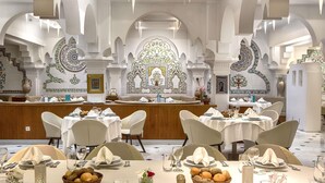 A restaurant with white tables, chairs, and a central bar area. - Sofitel Algiers Hamma Garden (Algiers)