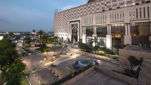 A modern building with a checkered facade, large windows, and a central courtyard with a fountain. - Sofitel Algiers Hamma Garden (Algiers)
