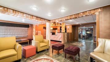 A hotel lobby with leather sofas, a reception desk, and a view of the dining area.
