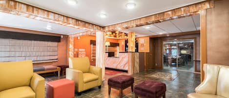 A hotel lobby with leather sofas, a reception desk, and a view of the dining area.