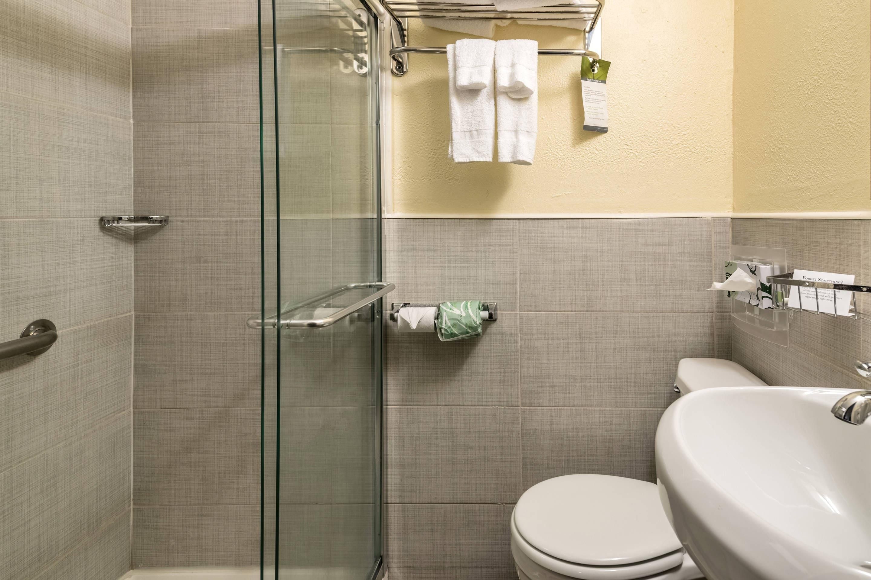 Un baño con cabina de ducha de vidrio, inodoro y lavamanos.