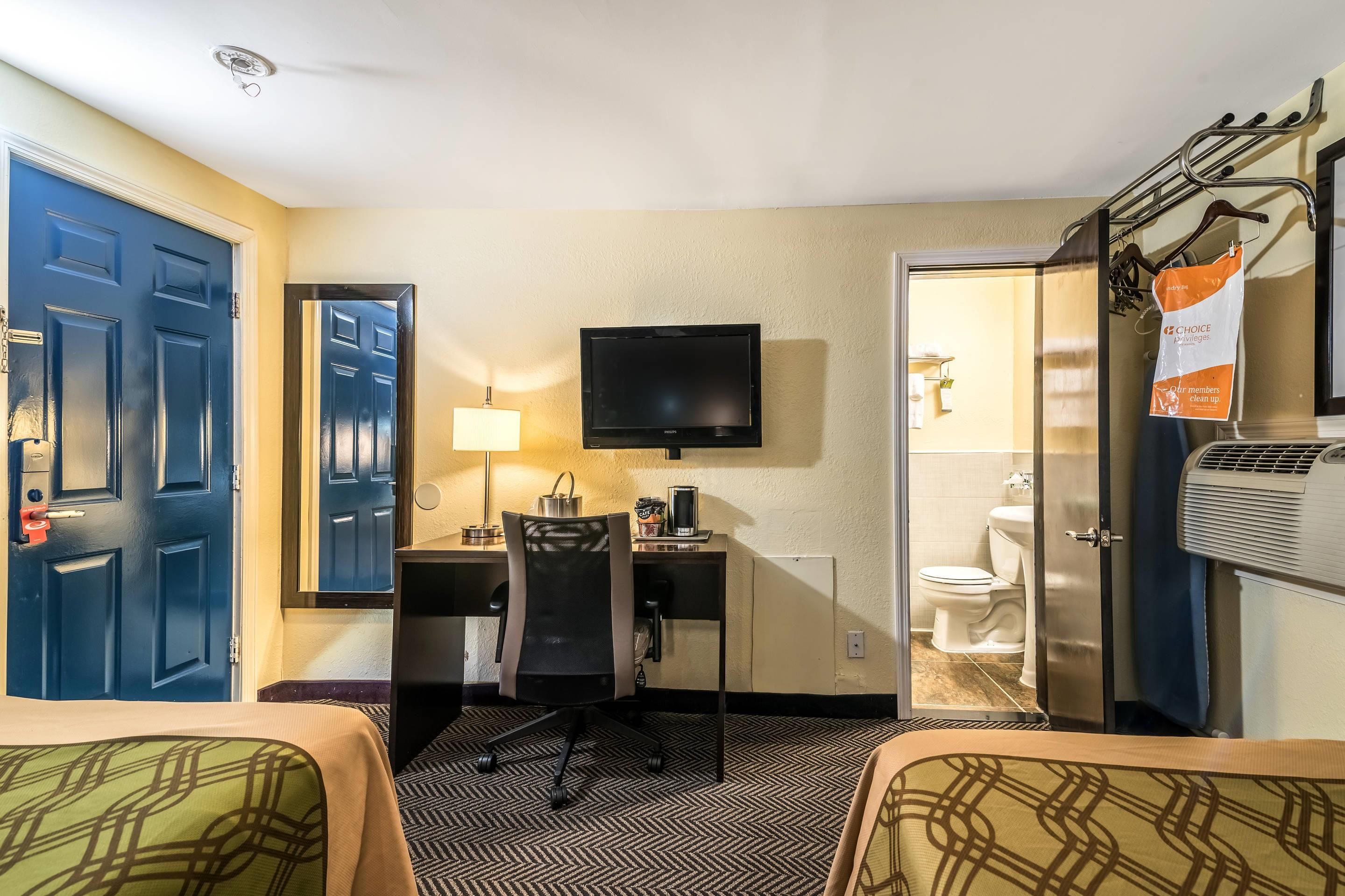Een hotelkamer met een bureau, een televisie, een bed en een badkamer.