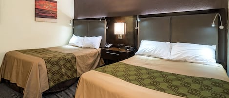 Habitación de hotel con dos camas, cada una con cabecero, mesitas de noche, lámparas y un cuadro en la pared.