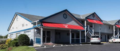 A two-story building with a red awning labeled 'office' and a parking lot with cars.
