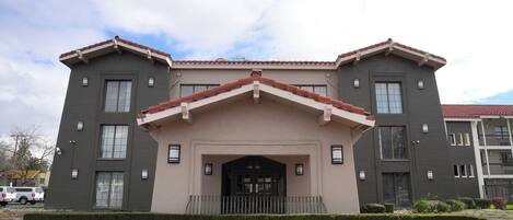 Un edificio de dos pisos con una entrada central, un pequeño porche y un tejado de tejas rojas.