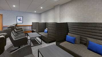 A modern lounge area with cushioned seating, a small table, and a framed picture on the wall.