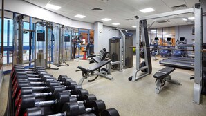 Academia com diversos equipamentos de exercício, incluindo halteres, bancos e máquinas de peso.