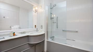 A modern bathroom with a glass-enclosed shower, a large mirror, and a curved vanity with a sink.