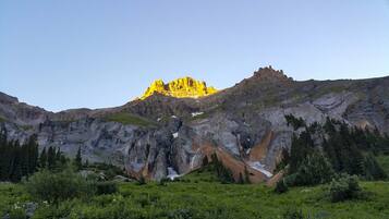 A mountain landscape with a prominent peak, rocky terrain, and surrounding greenery.