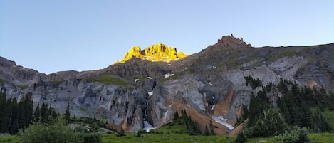 A mountain landscape with a prominent peak, rocky terrain, and surrounding greenery.