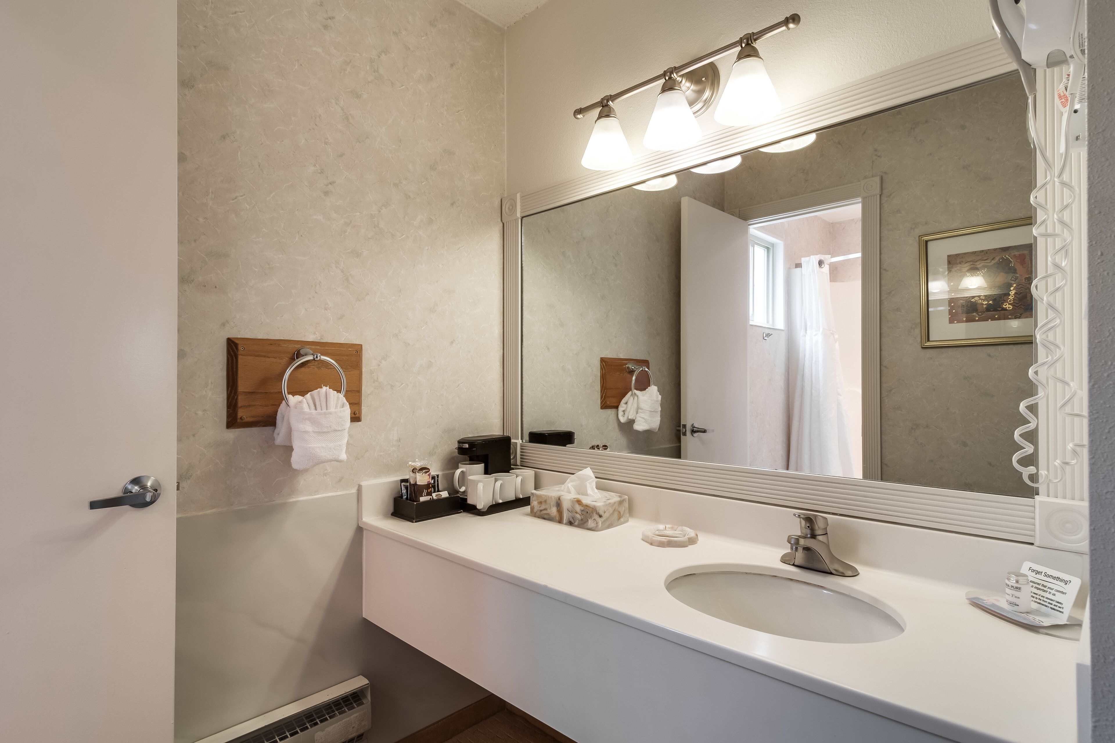 Un baño moderno con un espejo grande, un lavamanos blanco y un perchero para toallas.