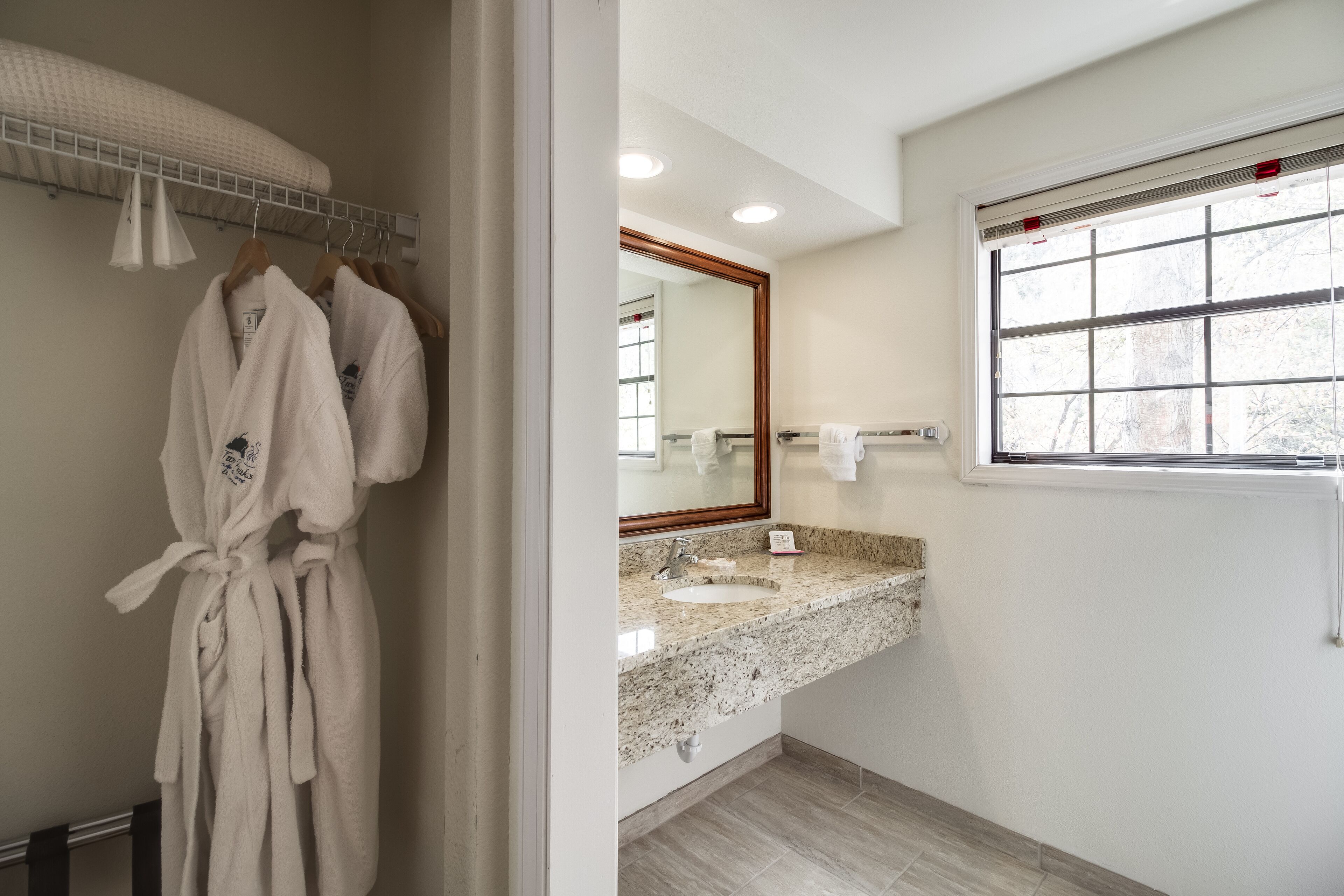A bathroom with a granite countertop, a mirror, and a window.