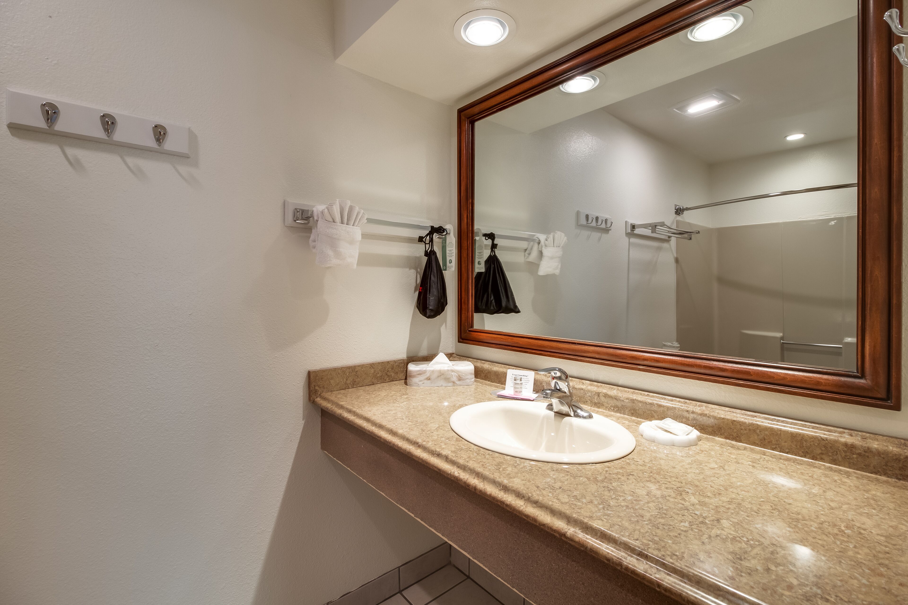 A bathroom with a sink, mirror, towel rack, and a shower area.