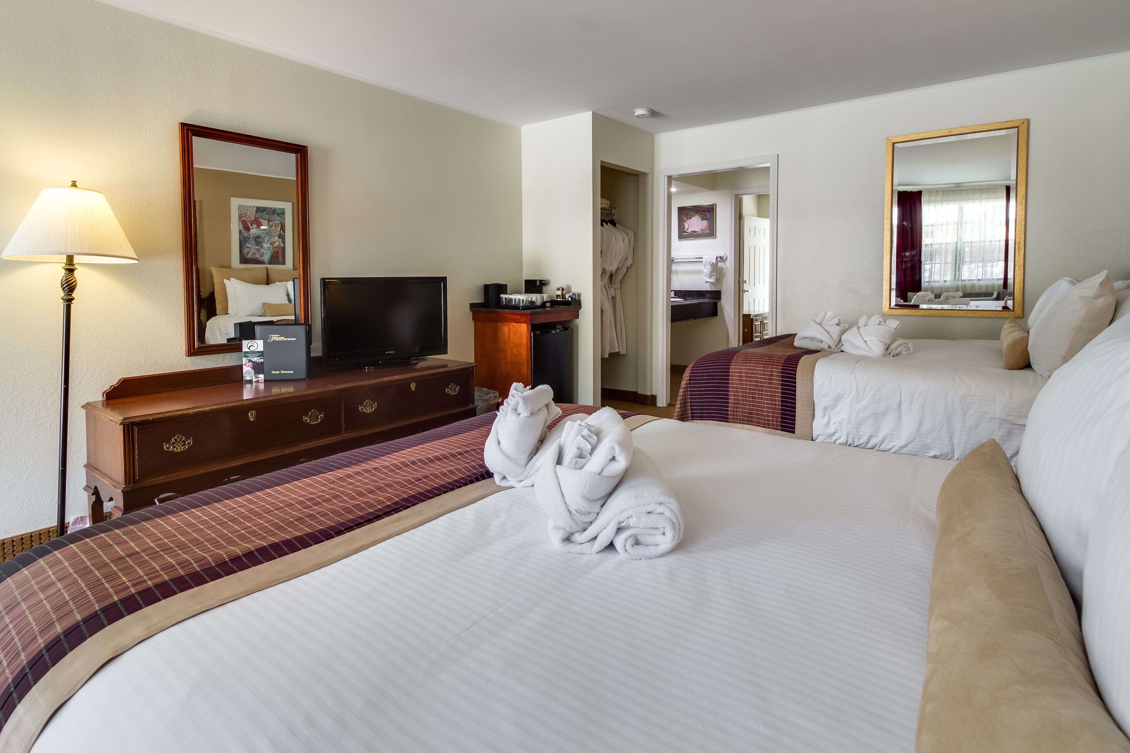 Habitació d'hotel amb dos llits, televisió, taulell i mirall.