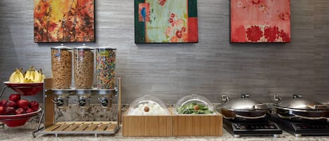 Montaje de bufé con diferentes platos y decoración mural.