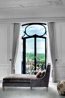 A modern room with a large window, a grey sofa, and a decorative ball.