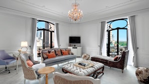 A spacious living room with a large sofa, a coffee table, and a television. The room has large windows with a city view. - The St. Regis New York (New York)