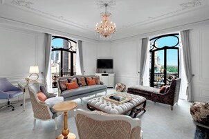 A luxurious living room with a sofa, armchairs, a coffee table, and a chandelier.