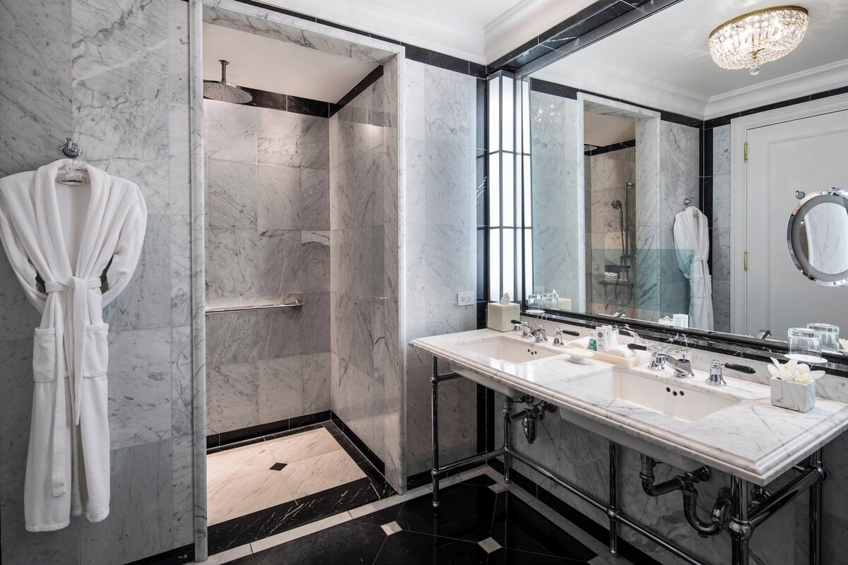 A modern bathroom with a walk-in shower, a large mirror, and a double sink.