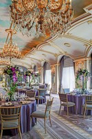 A luxurious dining room with ornate chandeliers, elegant table settings, and classic wooden chairs.