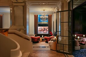 A luxurious lobby with a grand chandelier, plush seating, and a view into a high-end restaurant.