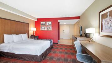 Une chambre d’hôtel avec un lit, un bureau, une chaise et une moquette rouge.