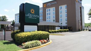 Un hotel La Quinta Inn & Suites con un cartel grande, un estacionamiento y la fachada del edificio.