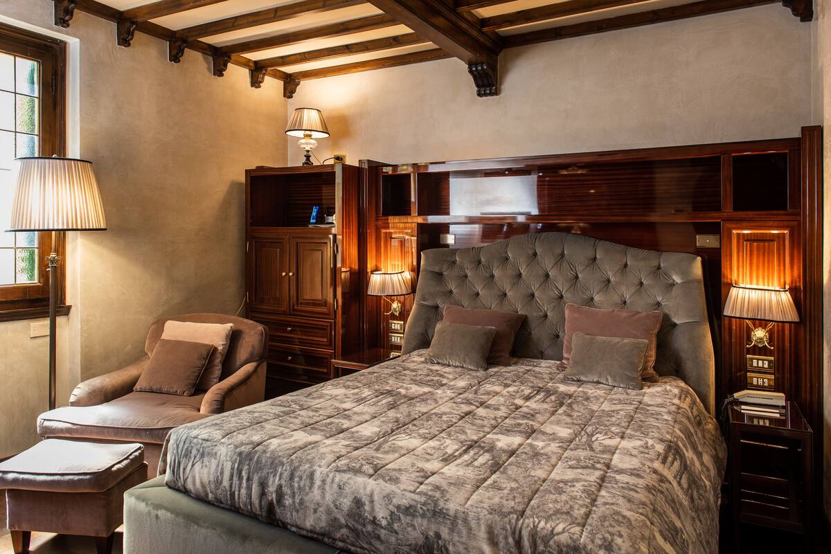 Ein Schlafzimmer mit einem großen Bett, einem Sessel, einem Schreibtisch und einem Kleiderschrank.