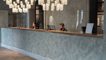 Un área de recepción con una lámpara de araña moderna, un mostrador de recepción y piso de madera.