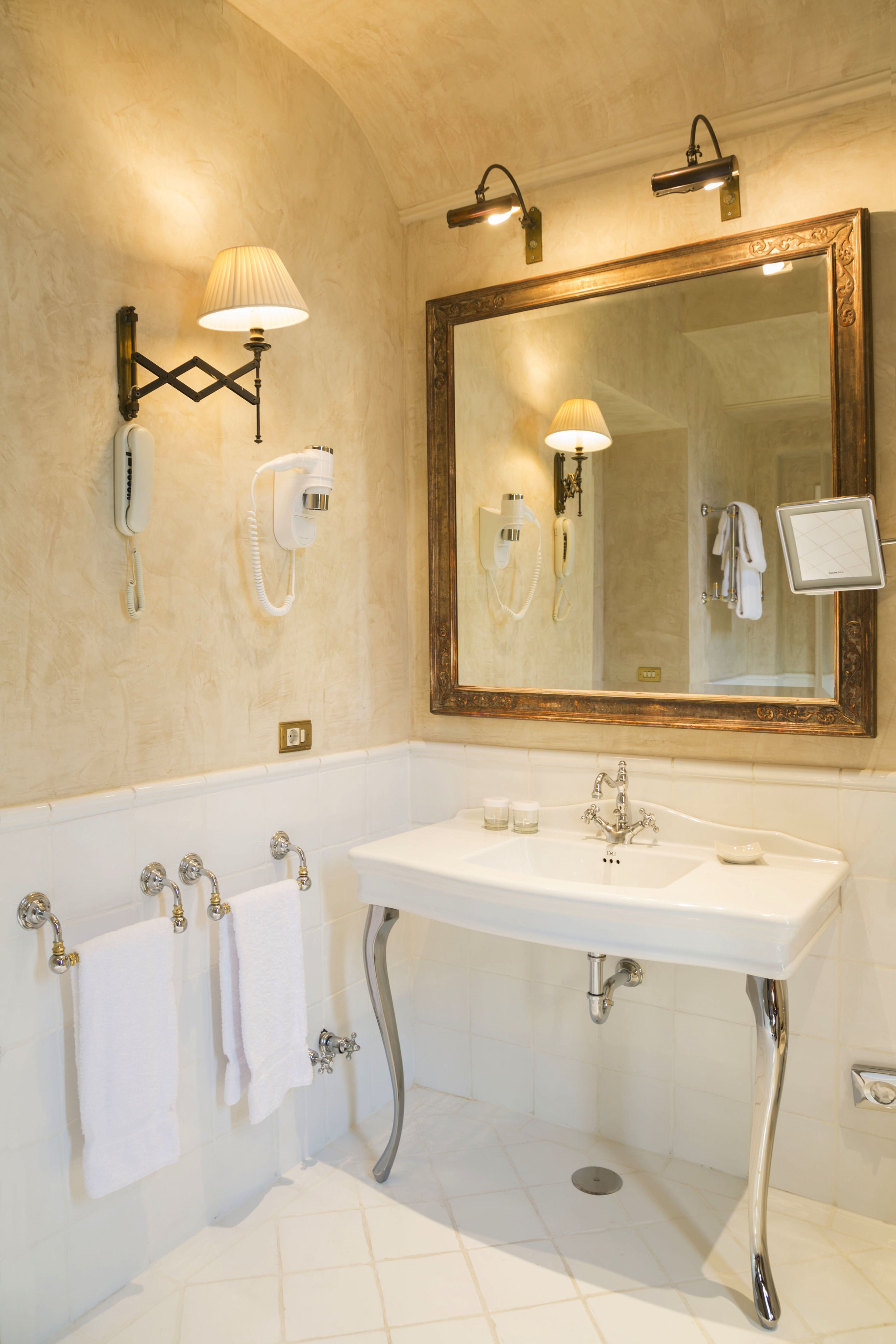 A bathroom with a large mirror, a bathtub, a sink, and two wall-mounted lamps.