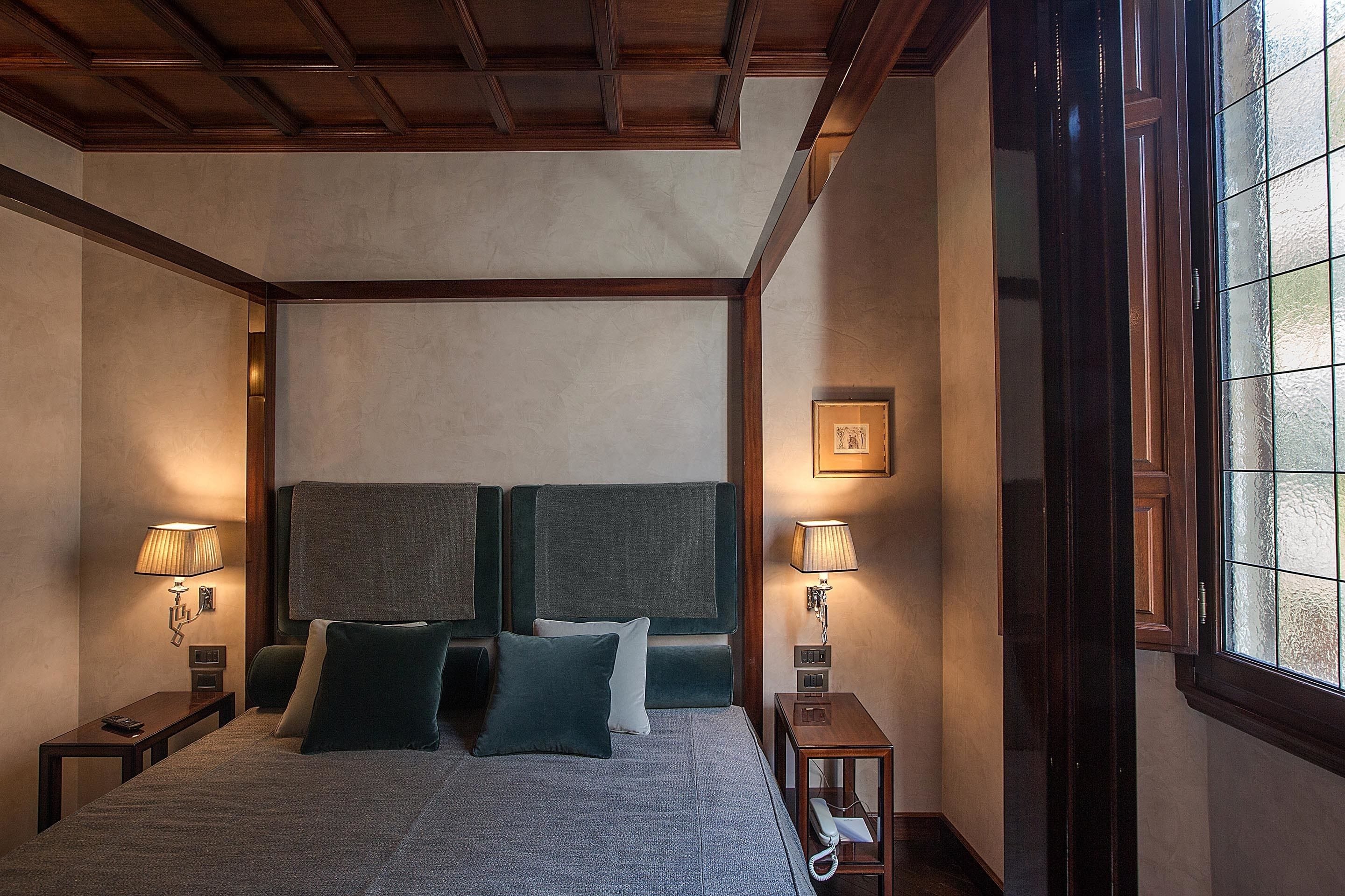 Camera da letto con un letto a baldacchino, due abat-jour e una finestra con vetro satinato.