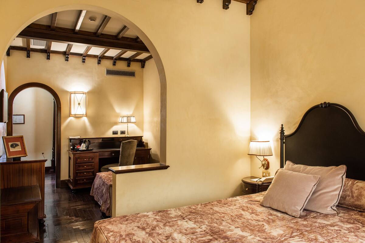 Ein Schlafzimmer mit Bett, Schreibtisch, Stuhl und Nachttisch mit Lampe.