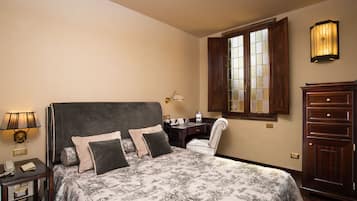 Habitación de hotel con una cama grande, un escritorio, una silla, una lámpara y un armario.