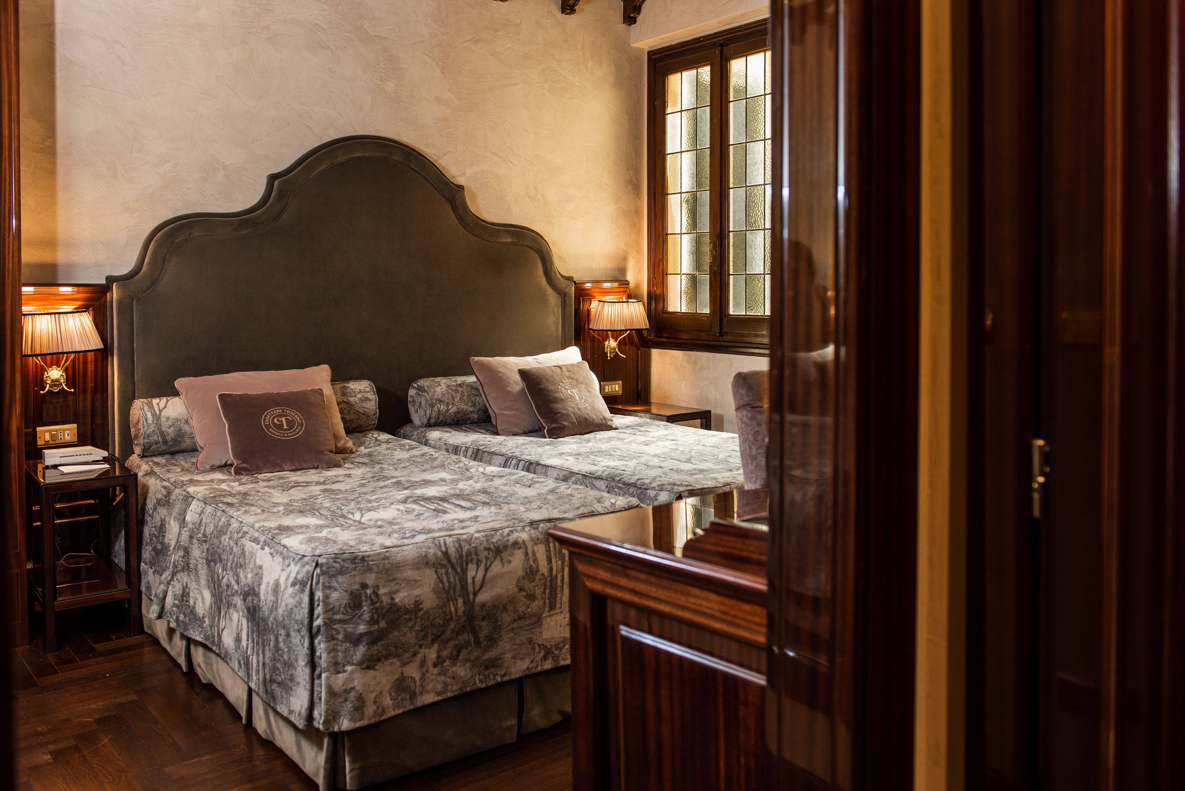 A double bed with a dark headboard, two bedside tables with lamps, and a window with a view.