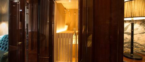 A wooden interior with a bench, a lamp, and a door leading to a room.