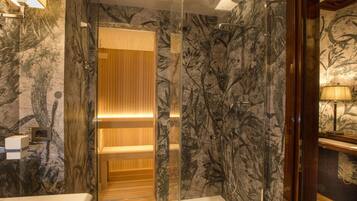 Un bagno moderno con cabina doccia in vetro, un mobile bagno in legno e una parete con motivo marmorizzato.
