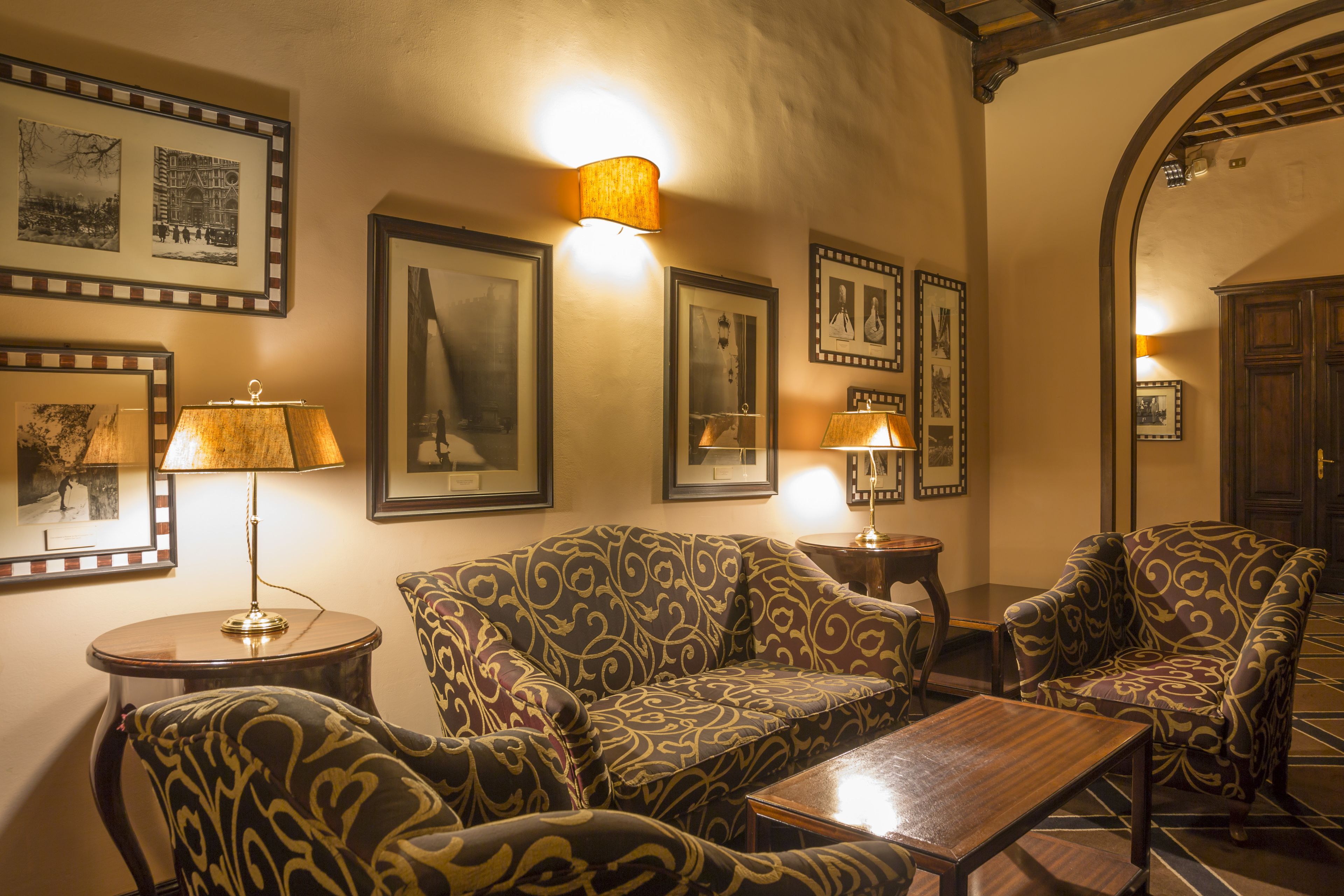 A cozy living room with patterned sofas, a wooden coffee table, and framed pictures on the walls.
