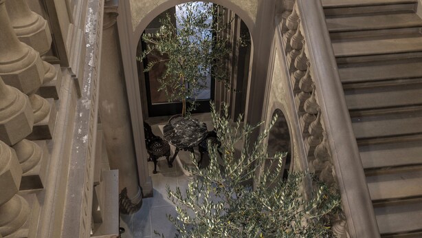 A grand staircase with ornate balustrades and a potted plant at the landing. - Grand Hotel Baglioni (Florence)