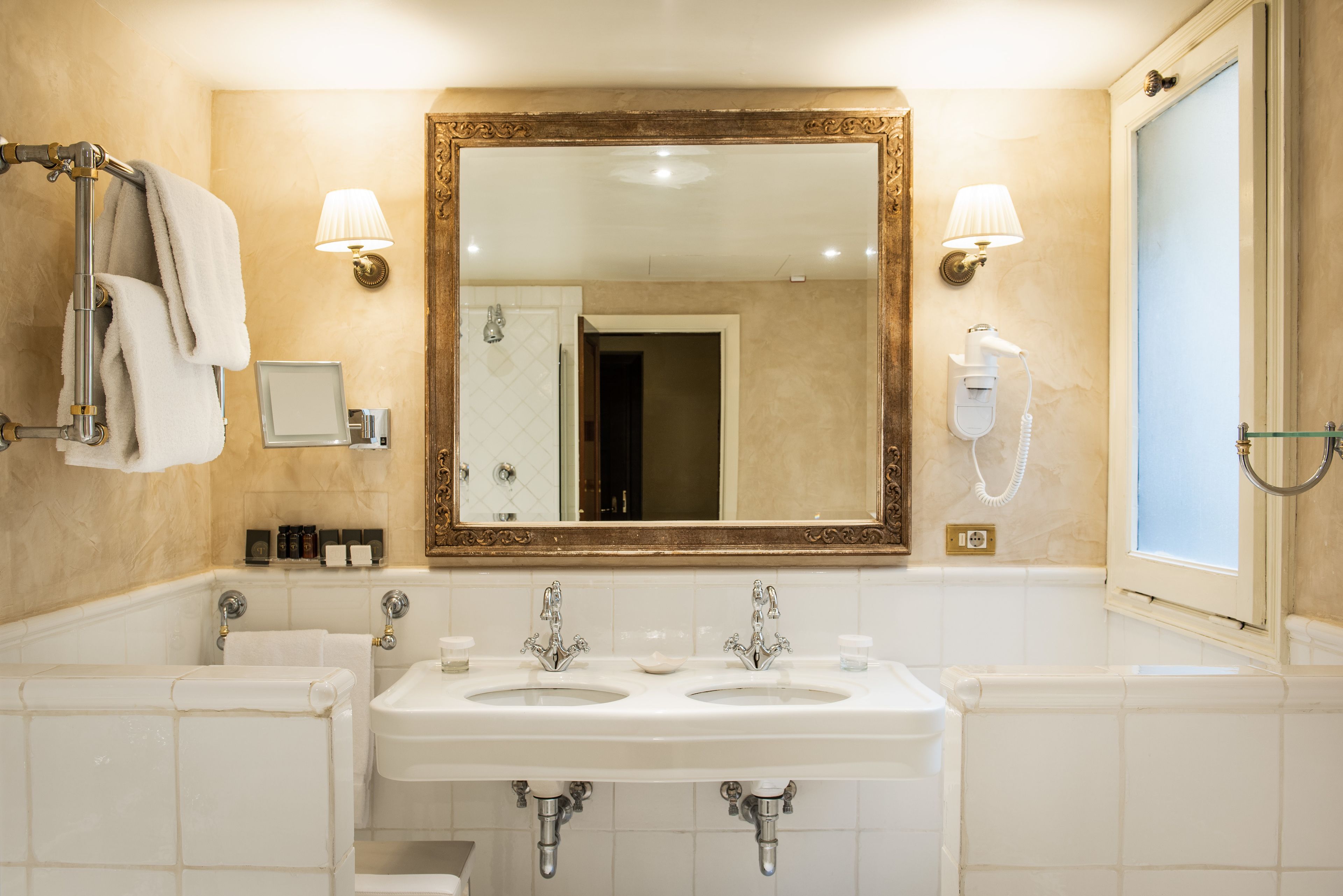 Un baño con dos lavamanos, un espejo grande y un secador de pelo en la pared.