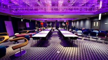Un salón de conferencias con una larga mesa, varias sillas y una alfombra estampada.