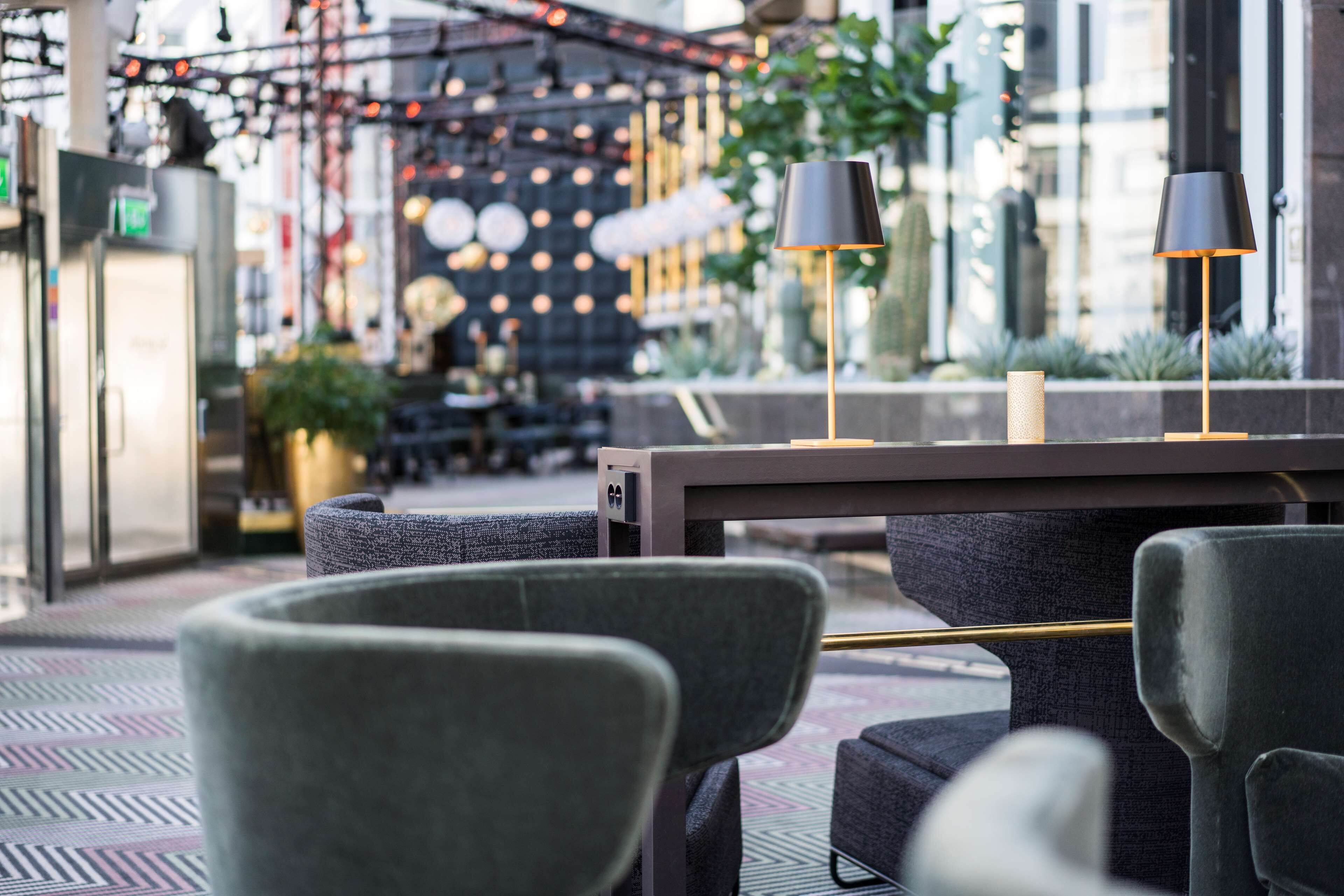 A modern outdoor seating area with a table and chairs, a lamp, and a decorative wall in the background.