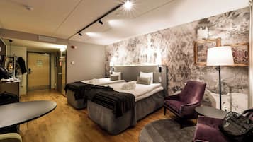 Ett hotellrum med två sängar, ett skrivbord, en stol och en soffa.