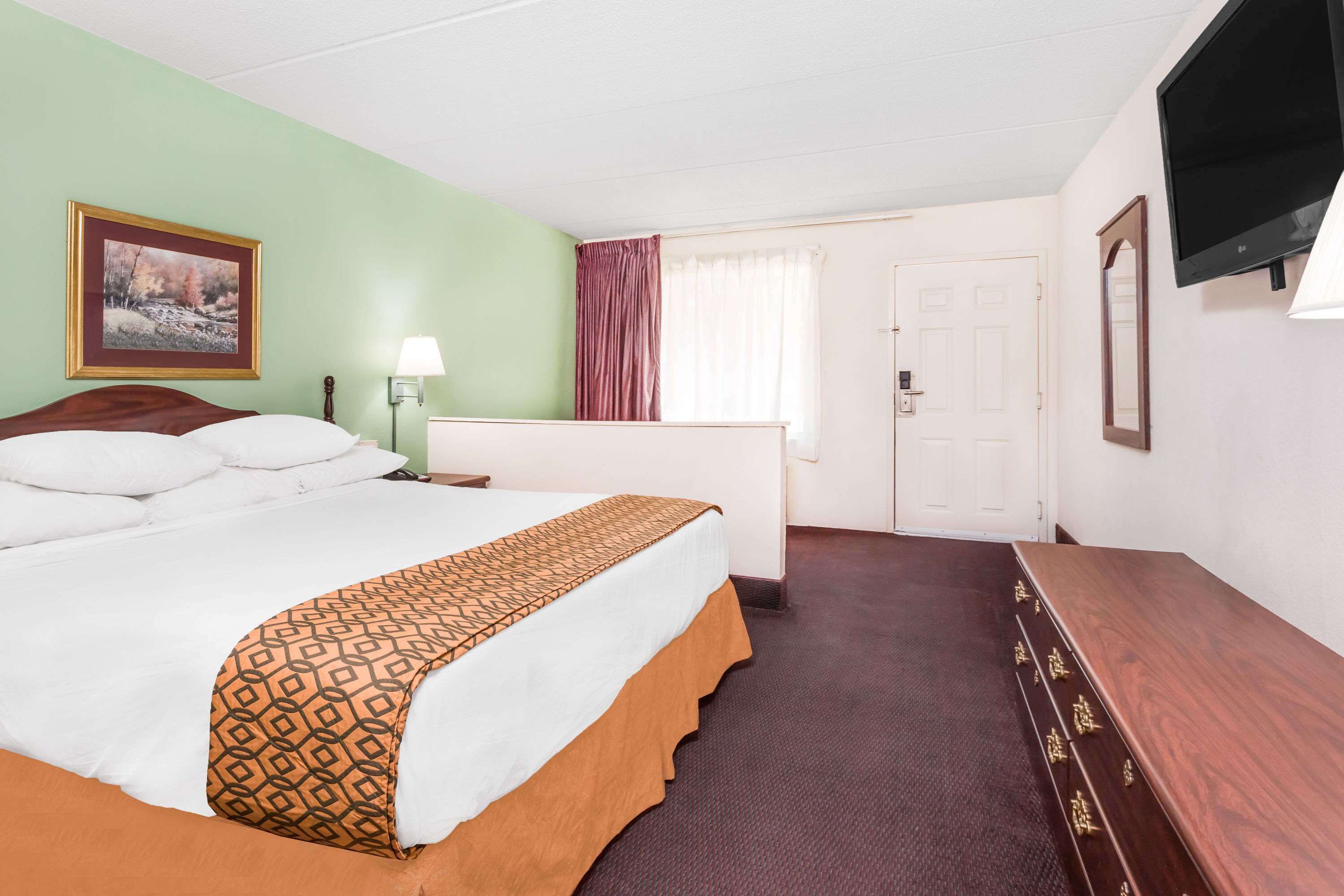 Ein Hotelzimmer mit einem Bett, einem Schreibtisch, einem Fernseher und einer Tür.
