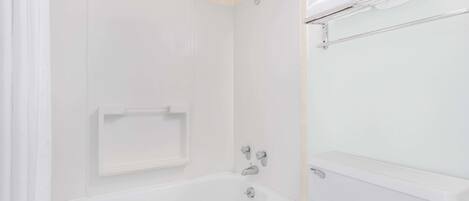 A white bathroom with a bathtub, a toilet, and a towel rack.