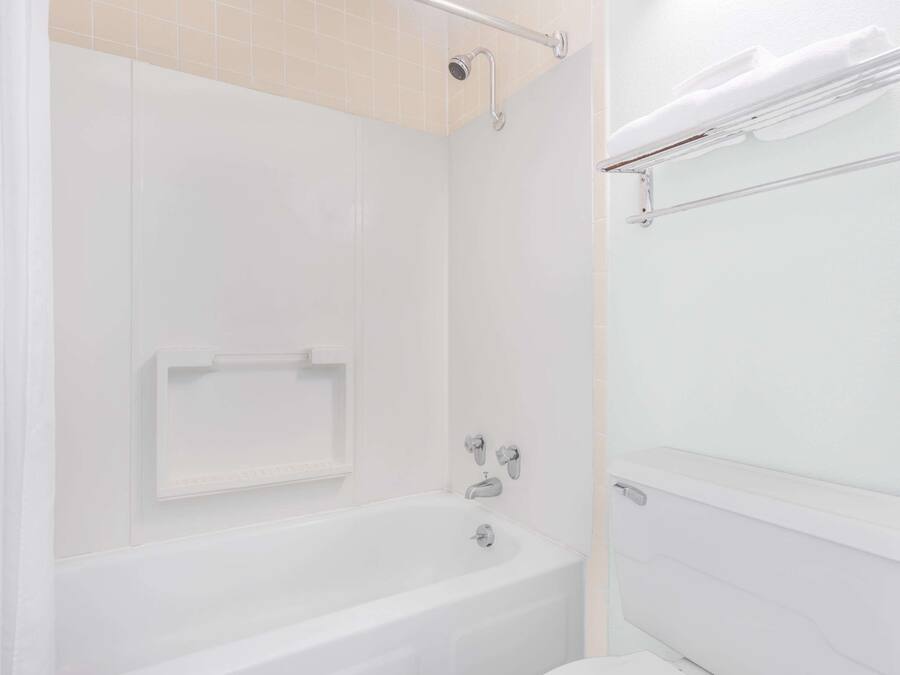 A white bathroom with a bathtub, a toilet, and a towel rack.