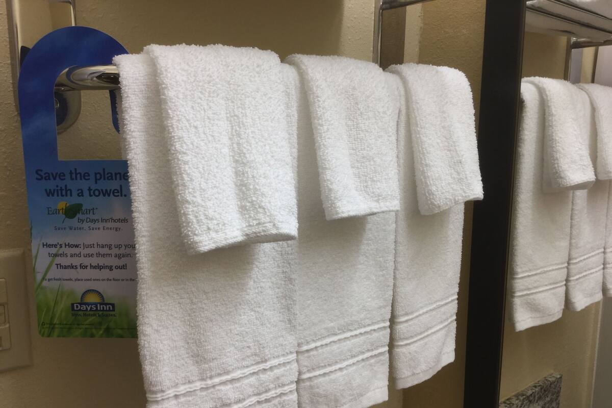 A row of white towels hanging on a rack in a bathroom.