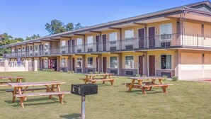 A multi-story motel with outdoor picnic tables and a mailbox.